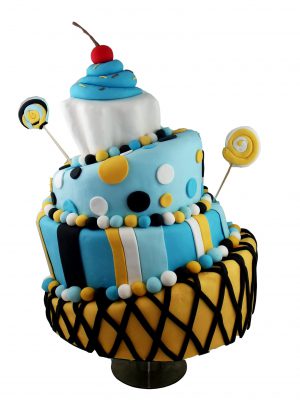 Tarta de varios pisos los cuales tienen tienen una inclinacion para lados diferentes., forrada fondan azul, blanco, y amarillo y decorada con bolitas y redondeles de fondant, piruletas con espirales de fondant y coronada con un cupcake tambien de fondant