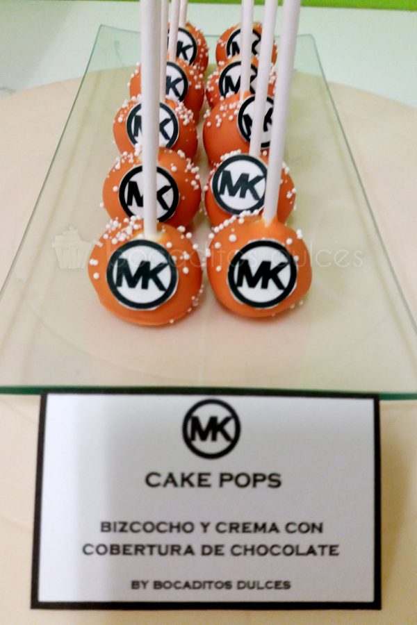 Cake pops son bolitas de bizcocho insertados en un palo de chupa chups, cubiertos de cholocales de color naranja y unas bolitas blancas y el logo de la empresa en su frontal realizado con papel de azúcar.
