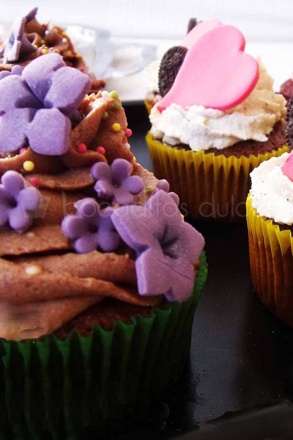 Cupcakes de bizcochos de diferentes sabores decorados con Buttercream de distintos sabores y decorados a su vez con flores de fondant y corazones.