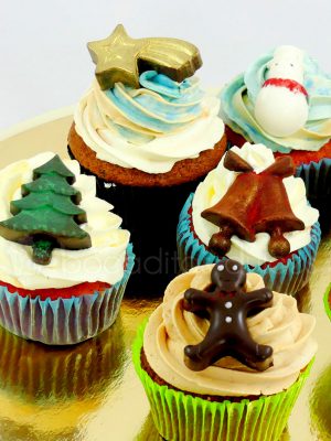 Cupcakes decorados con buttercream de vainilla, y encima pequeñas chocolatinas com arbol de navidad, estrella de oriente, muñeco de nieve, campanas y muñequito de jengibre.