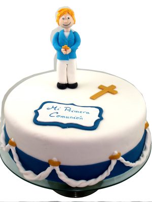 Tarta cubierta de fondant blanco, y decorada con cuerdas en fondant, cruz de color oro tambien de fondant y cartel de primera comunion en fondant
