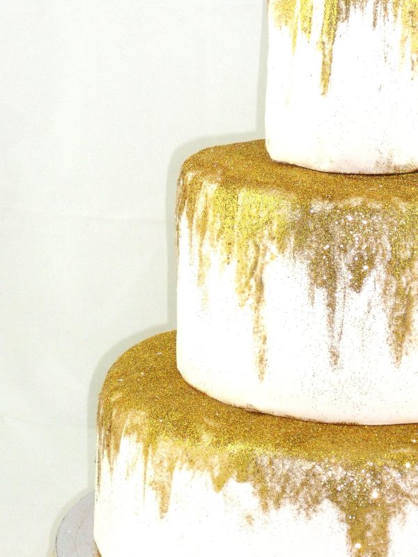 Detalle de tarta blanca de 3 pisos con purpurina dorada
