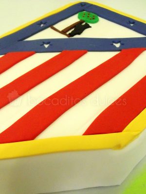 Tarta tallada con la forma del escudo del atlético de Madrid.
