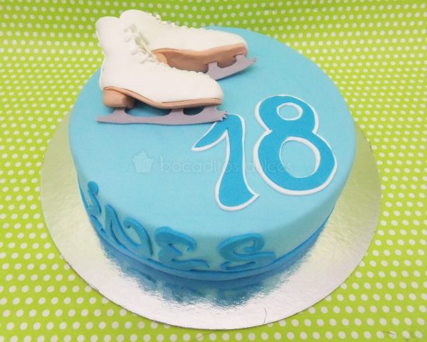 Tarta sencilla forrada con fondant azul, nombre y años del cumpleañero y decorada con dos patines para el hielo modelados en fondant.