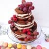 Mesa dulce de estilo rustico compuesta por minicupcakes de distintos sabores, galletas con chips de chocolate, macarons de distintos sabores y tarta de desnuda de tres pisos decorada con frutas del bosque.