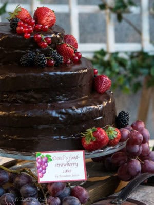 Tarta de tres pisos, forrada de ganache de chocolate y decoarada con frutos rojos.