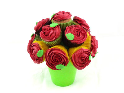 cupcakes de vainilla con buttercream decorando en forma de rosa en color rojo decorados con una hojita de fondant, todos ellos colocados de tal manera que parece un ramo de rosos