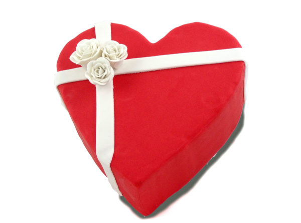 Tarta en forma de corazon forrada con fondant de color rojo, y dos tiras de fondant blanco decoradas con tres rosas blancas de fondant