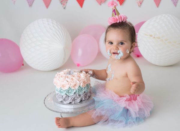 Delicada tarta de rosetones de crema en varios colores para sesión de fotos con bebé