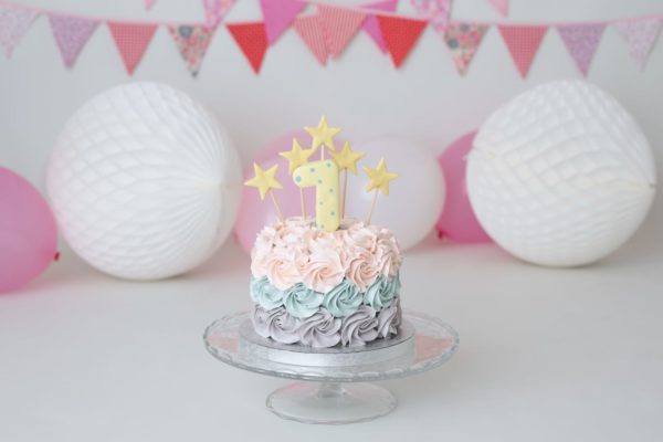 Delicada tarta de rosetones de crema en varios colores para sesión de fotos con bebé