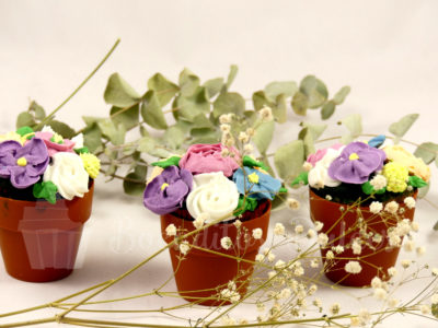 3 cupcakes con flores y maceta de chocolate