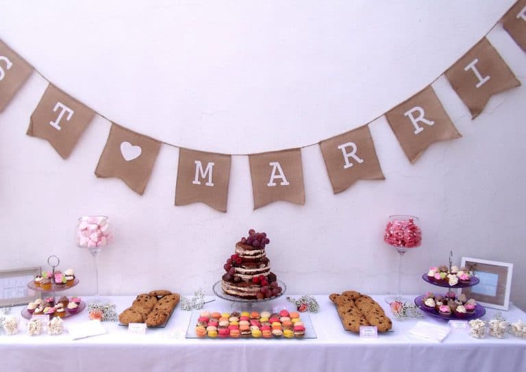 Mesa dulce con tarta desnuda decorada con frutos rojos, gominolas, mini Cupcakes, macarons y galletas con chispas de chocolate