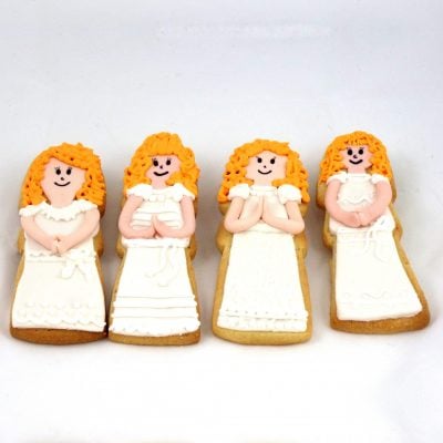 Galletas de comunión con forma de niña, decoradas con traje blanco en fondant.