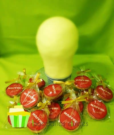 Tarta modelada con forma de bombilla, la cual esta cubierta con fondantr¡ amarillo y bajo de fondant color plata dondo forma al casquillo de la bombilla. Galletas redondas de mantequilla decoradas con papel de azúcar personalizado.
