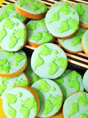 Galletas de mantequilla con forma circular decoradas con fondant y glaseado real dando forma a un mapamundi.
