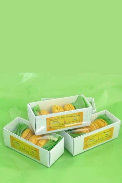 Macarons amarillos de sabor limon en cajita de cuatro unidades con logotipo personalizado.