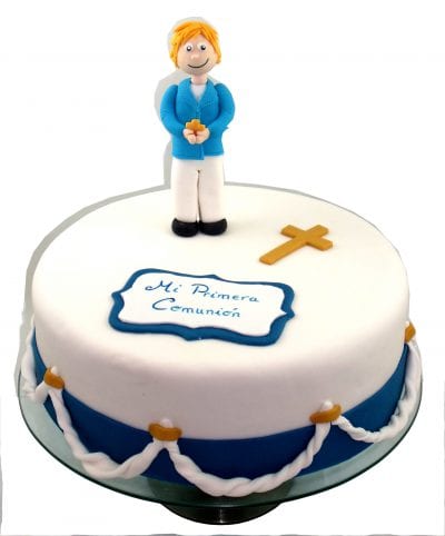 Tarta cubierta de fondant blanco, y decorada con cuerdas en fondant, cruz de color oro tambien de fondant y cartel de primera comunion en fondant