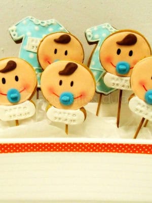 Galletas piruleta de fondant con la carita de un bebe, y bodys de bebe.