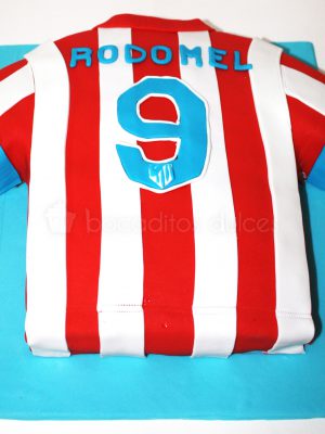Tarta tallada con forma de camiseta del equipo de futbol del atletico de madrid.