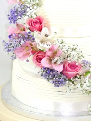 Tarta cubierta de buttercream blanco decorada con flores naturales.