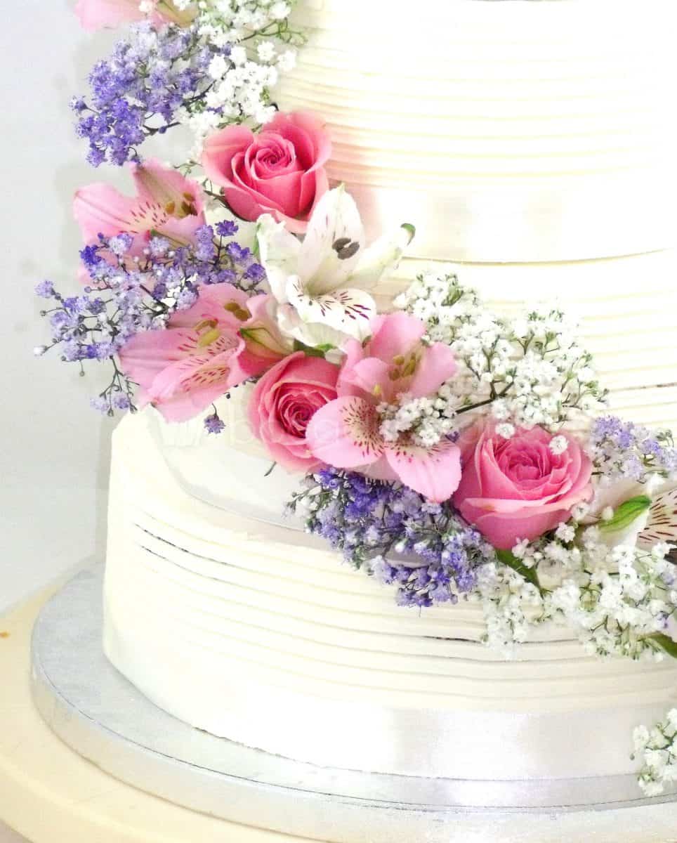 Tarta cubierta de buttercream blanco decorada con flores naturales.