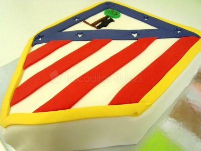 Tarta tallada con la forma del escudo del atlético de Madrid.