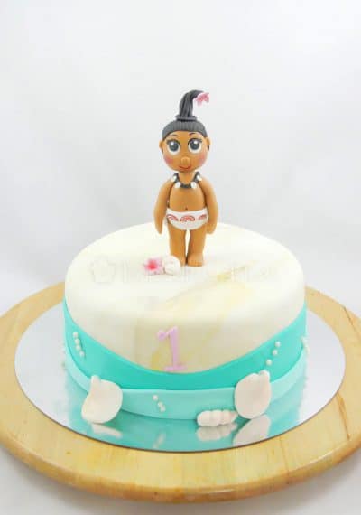 Tarta forrada con fondant blanco, y decorada alrededor con fondant azul emulando agua y pequeñas conchas en fondant y la protagonista de la pelicula en fondant.