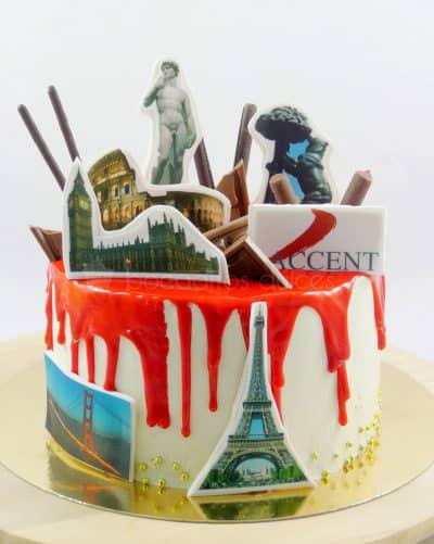 Tarta cubierta de buttercream blanca con chocolate rojo fundido, decorado con diferentes monumentos del mundo en papel de azúcar.