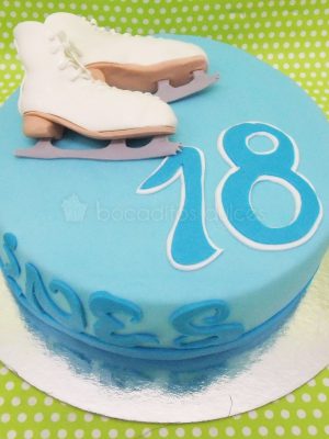 Tarta sencilla forrada con fondant azul, nombre y años del cumpleañero y decorada con dos patines para el hielo modelados en fondant.