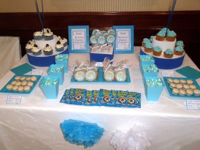 Mesa dulce en color azul, compuesta por cupcakes con buttercream de color azul sabor vailnilla, cajitas de palomitas de color azul, galletas redondas con palo, decoradas con papel comestible de azucar, galletas de mantequilla redondan decoradas con papel comestible de azúcar, bolsitas de chuches, y macarons de color blanco