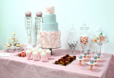 Mesa compuesta por cake pops, variesad de gominolas, nini pastelitos, vasitos con batidos de fresa y nata, macarons, cupcakes y tarta personalizada de cuatrao pisos